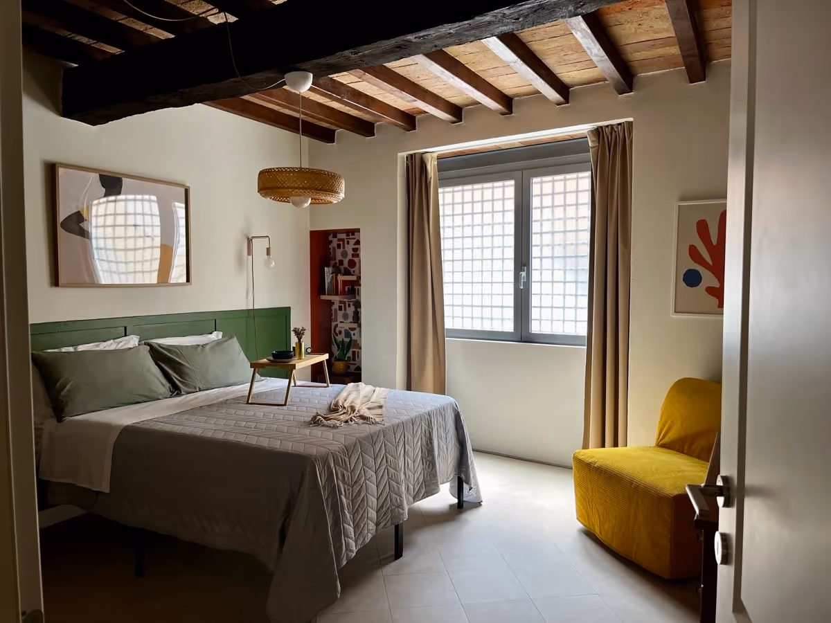 Camera da letto con letto matrimoniale, testiera verde e travi a vista