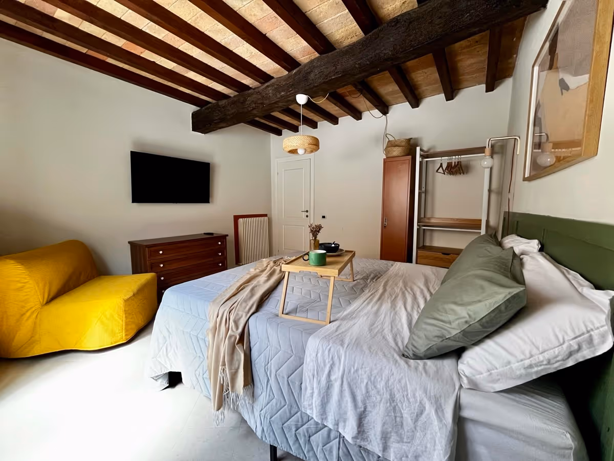 Camera da letto con Smart TV 55", poltrona letto gialla e zona armadio