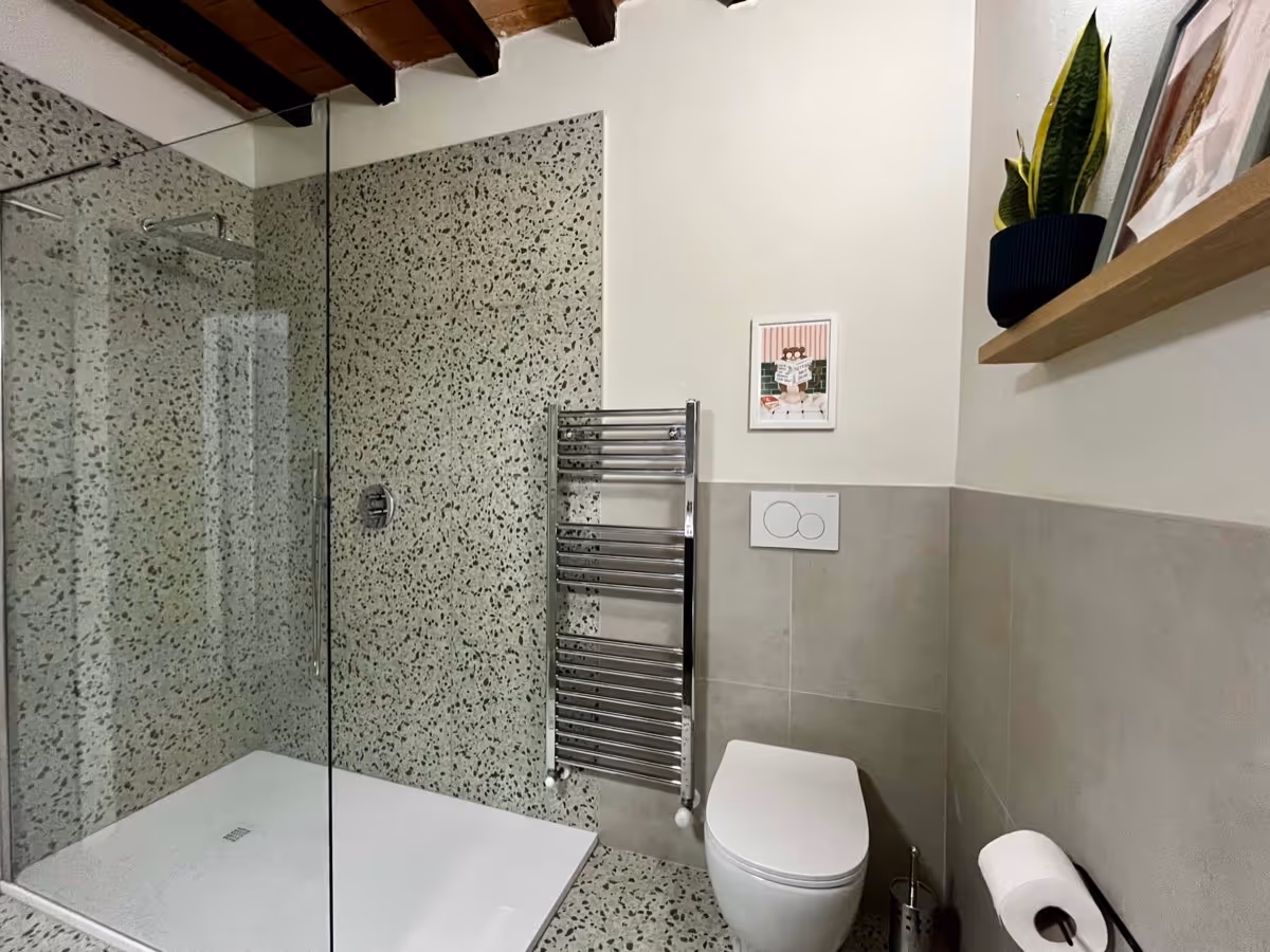 Ampia doccia walk-in con piatto a filo pavimento e scaldasalviette